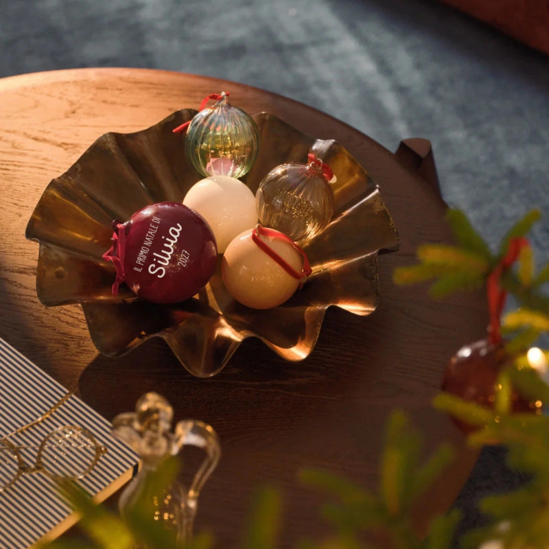 Palline di Natale in vetro personalizzate, bordeaux, bianca e beige, in un vassoio di metallo accanto ai rami dell'albero