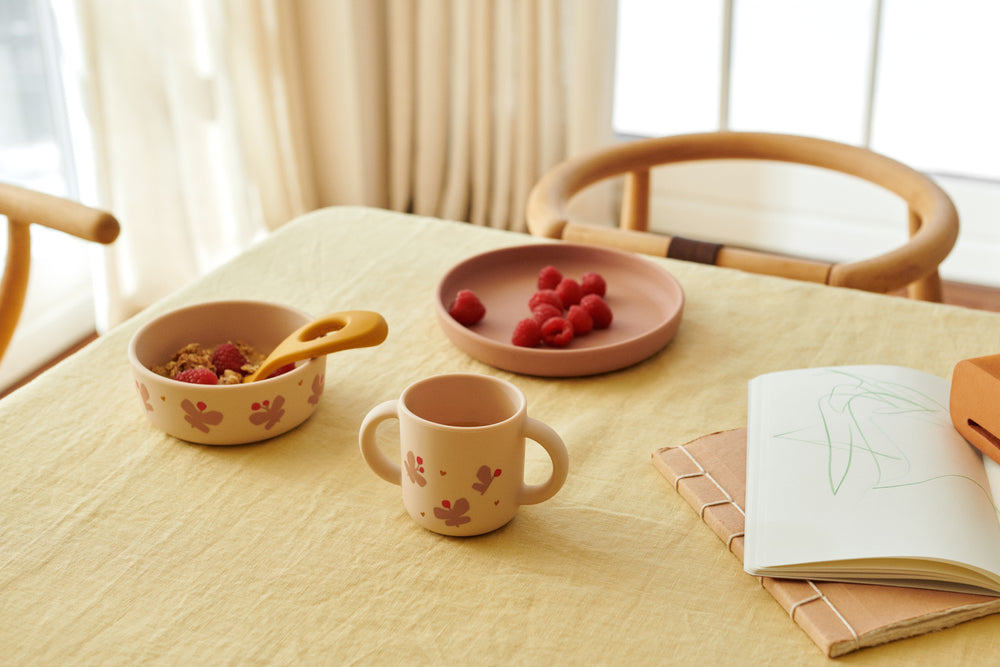 un set pappa minimalista con farfalline di colore beige e rosa su una tavola