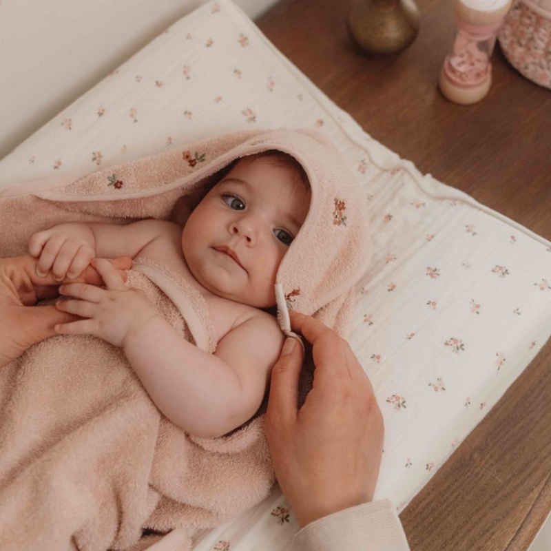 Bimba su fasciatoio a fiorellini bianchi appoggiata su accappatoio triangolo rosa little dutch