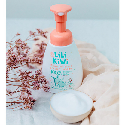 mousse detergente per bambini bianca e arancio appoggiata su una mussola color beige e fiori secchi