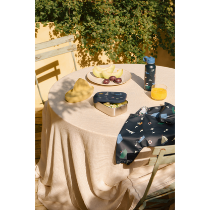 tavola apparecchiata all'aperto con lunchbox blu e borraccia e bavaglio liewood