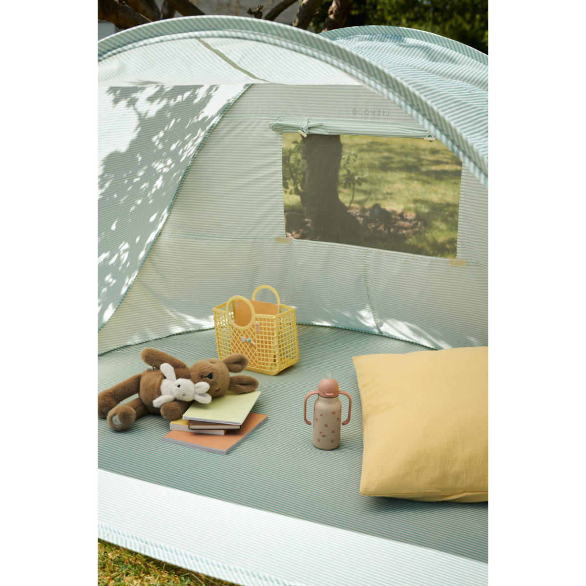 tenda azzurra con dentro dei peluches e una borraccia rosa liewood con borsa gialla in silicone